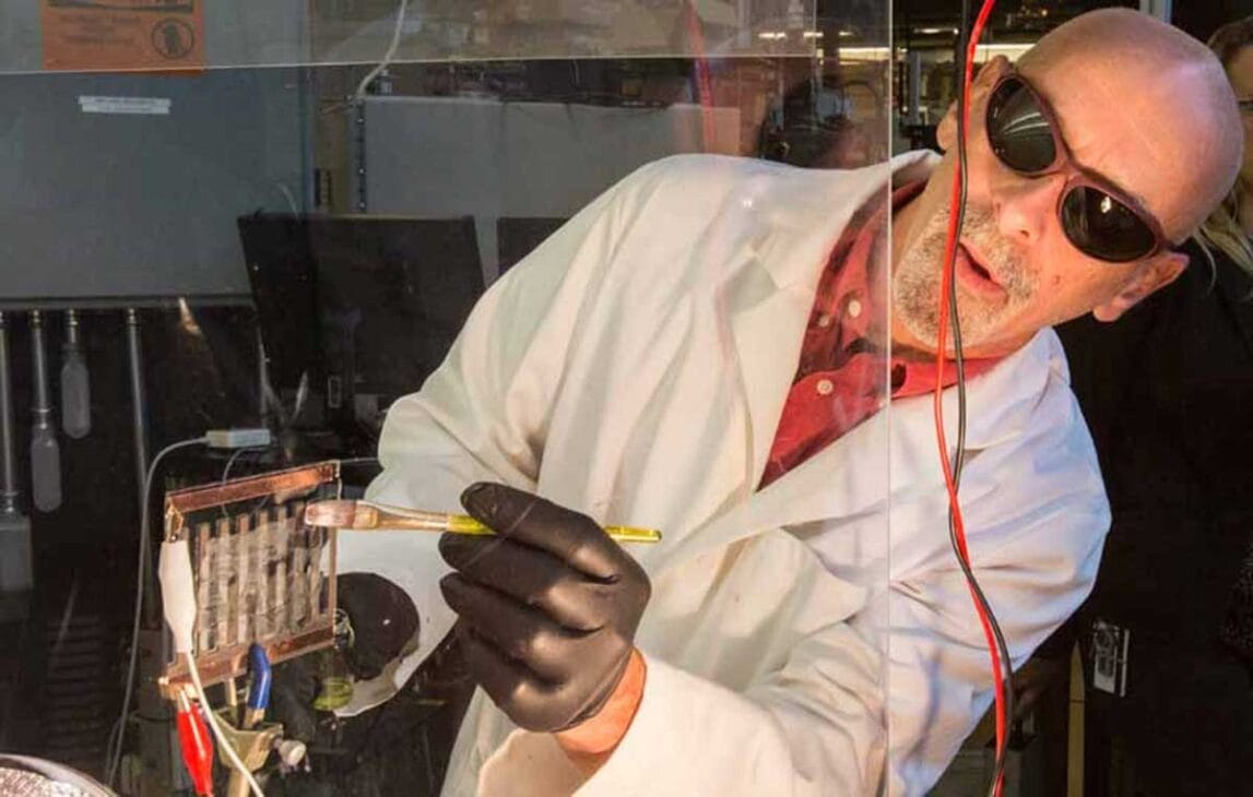 Scientist painting a glass surface with perovskite paint. Image source: nrel.gov