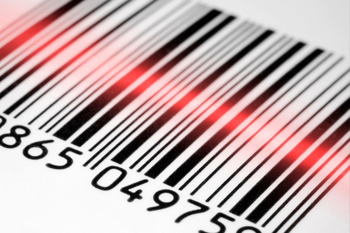 Feixe de laser vermelho escaneando um código de barras branco e preto.