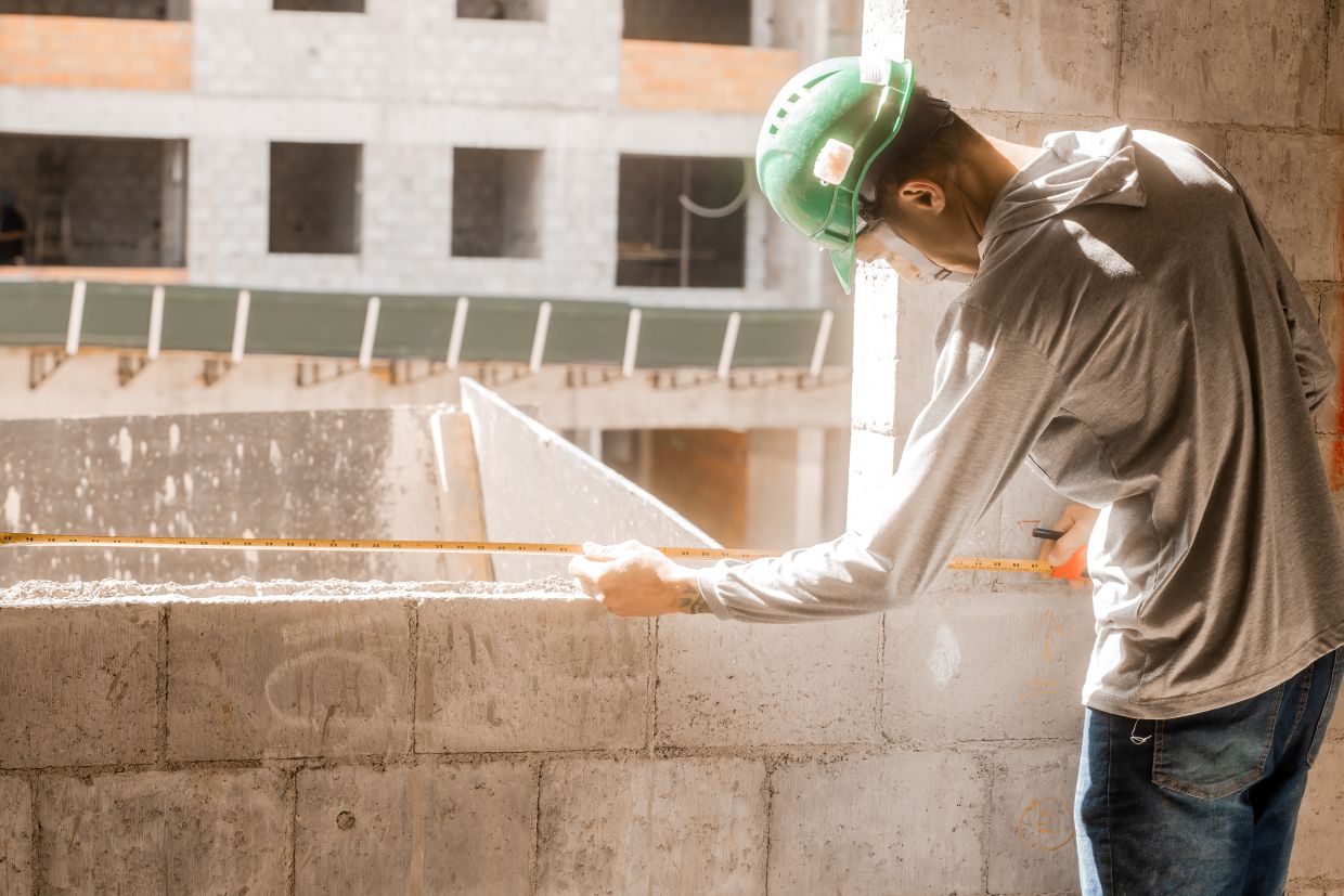 Trabalhador da construção civil mede parede em obra de prédio residencial em Sorocaba