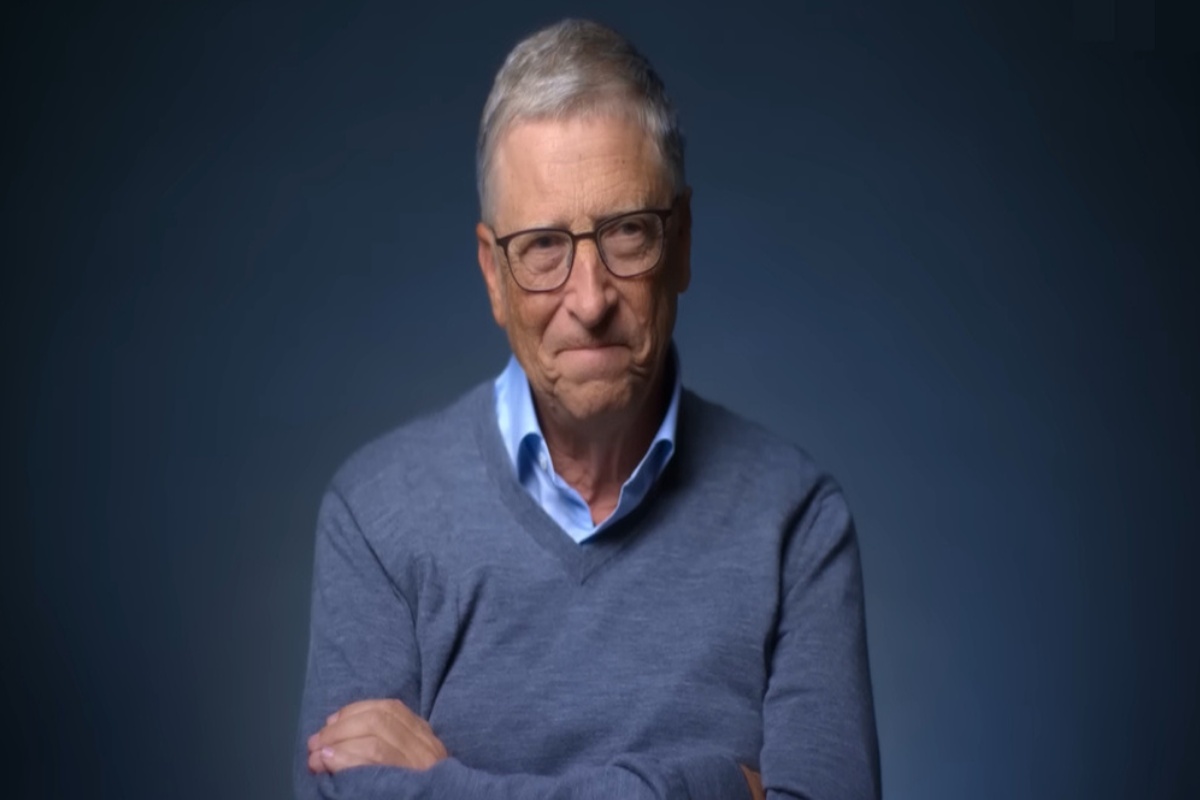 Bill Gates cruzando os braços com expressão séria, fundo escuro