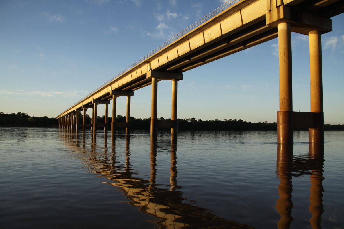 Ponte Integração atravessando rio com pilares refletidos na água ao entardecer