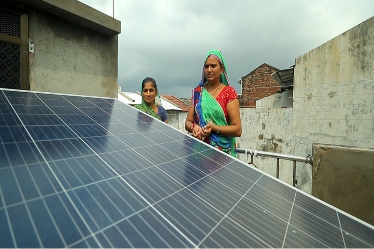 Mulheres indianas em vila rural inspecionam painéis solares instalados no telhado