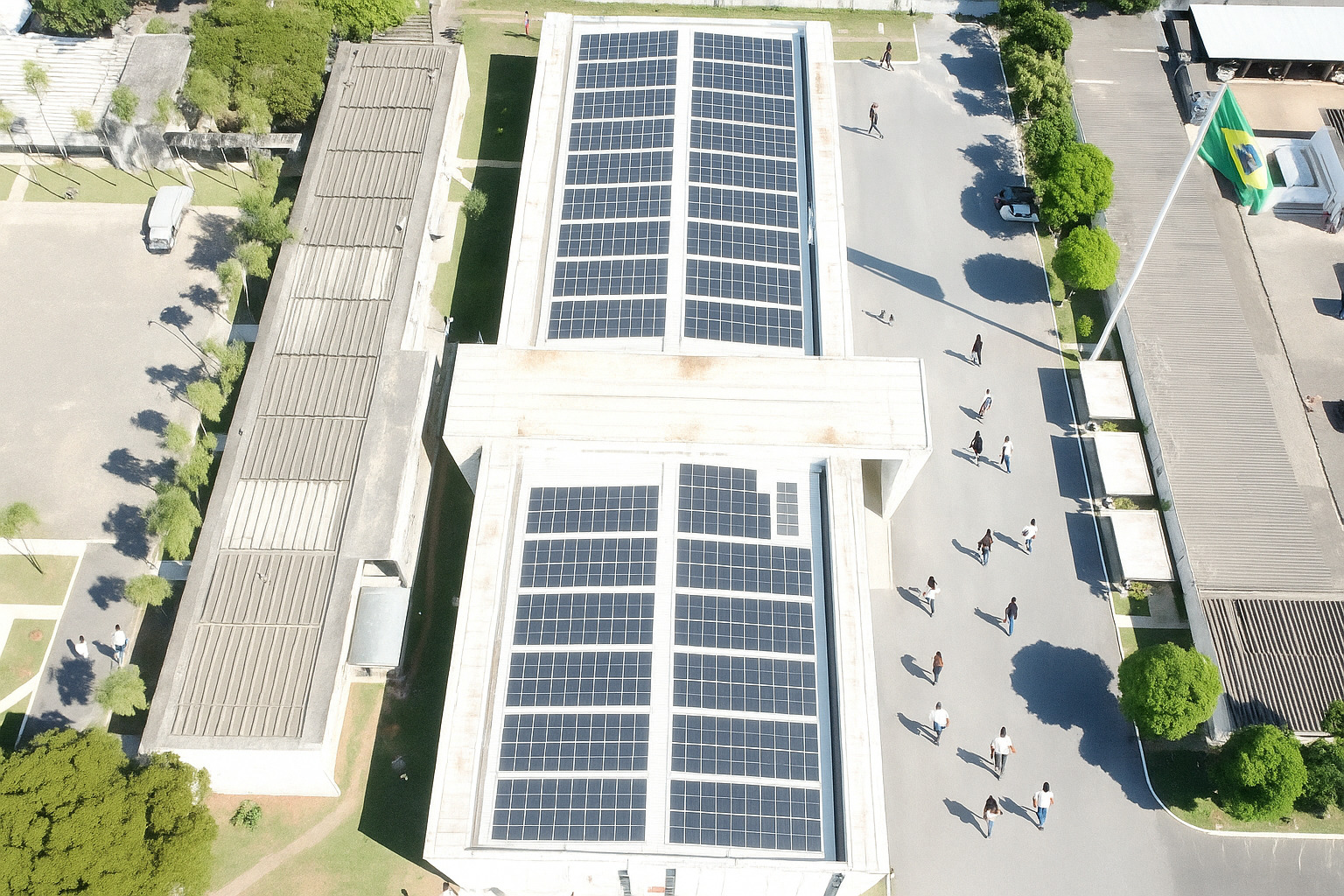Pessoas caminhando ao redor de prédio com painéis solares durante o dia
