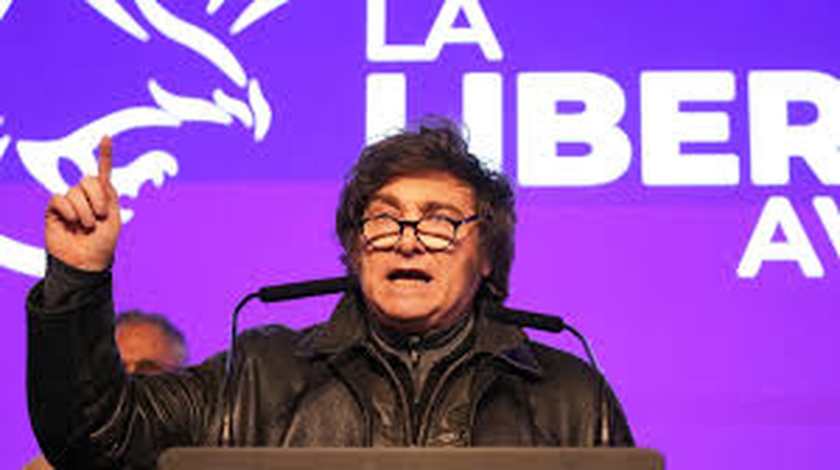Javier Milei discursando com fundo roxo do partido La Libertad Avanza