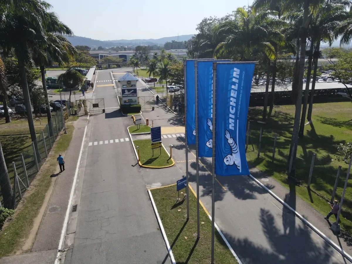 Entrada da fábrica da Michelin com bandeiras e portaria ao fundo
