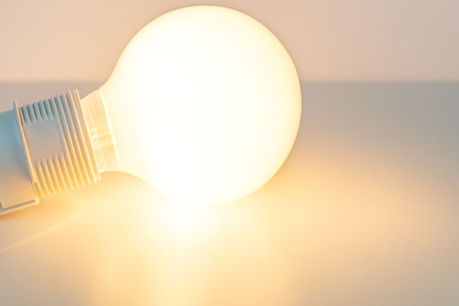 Lâmpada acesa iluminando uma superfície branca, simbolizando economia de energia e inovação tecnológica.