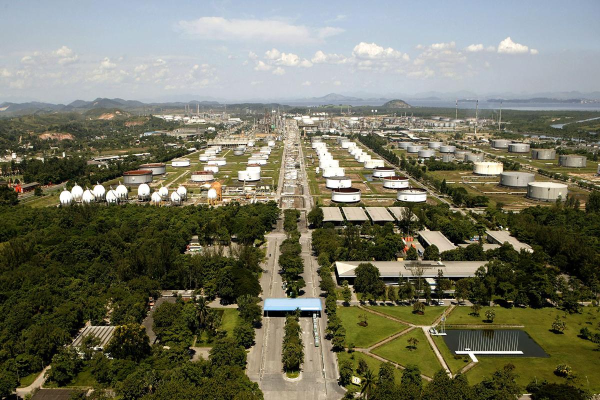 Vista aérea da Refinaria Duque de Caxias (Reduc), da Petrobras, no Rio de Janeiro, com tanques metálicos e áreas verdes que simbolizam inovação e sustentabilidade energética.