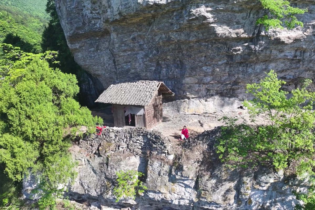 Em Guizhou, a casa de madeira pendurada em penhasco esconde um templo antigo, uma trilha extrema e a história de um morador que mantém vivo o caminho dos fiéis.