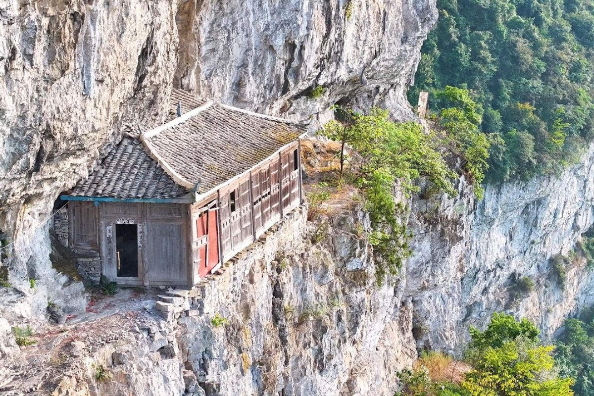 Nas montanhas de Guizhou, uma casa centenária suspensa revela uma construção impossível, alcançada por um acesso arriscado que leva a um templo secreto no alto do penhasco.