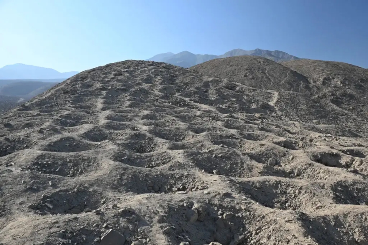 Vista aérea do Monte Sierpe, no sul do Peru, mostrando milhares de buracos escavados na encosta rochosa, alinhados com precisão milimétrica e cercados pelas montanhas áridas dos Andes.