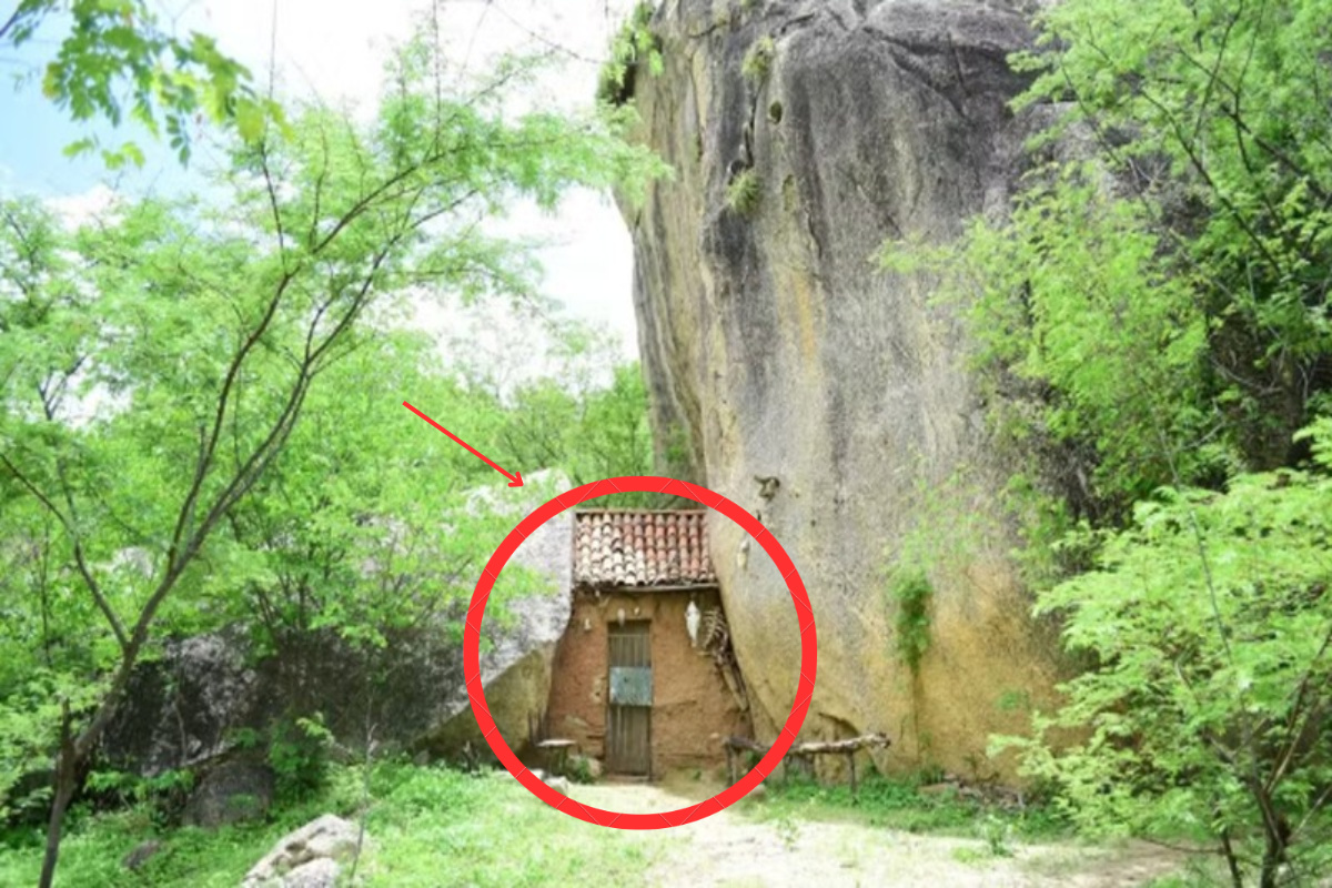 Casinha de taipa construída entre duas rochas gigantes no sertão do Ceará, destacada por um círculo vermelho e seta indicativa.