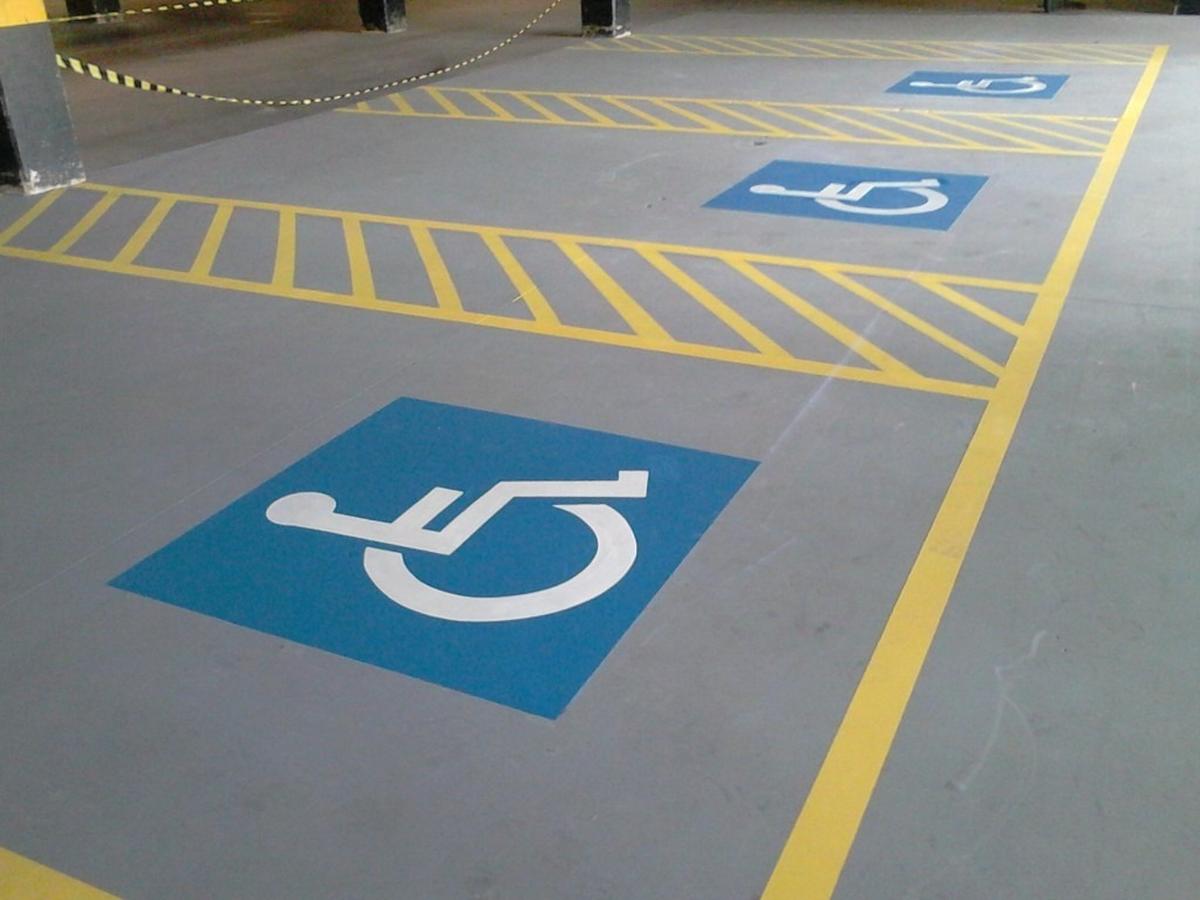 Vagas de estacionamento para pessoas com deficiência demarcadas com símbolo azul e linhas amarelas em área interna.