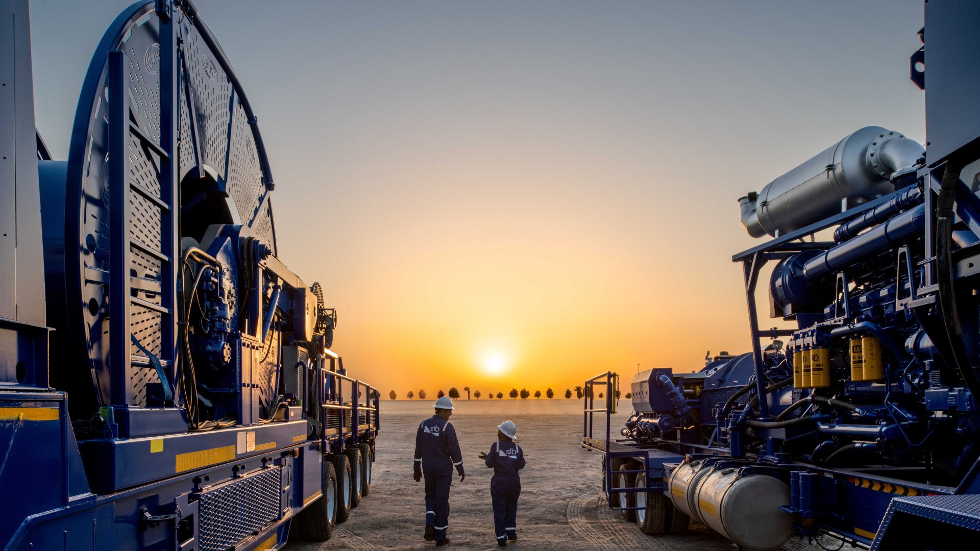 Equipamentos industriais de gás não convencional operados pela SLB em campo terrestre no deserto, com tecnologia avançada para estimulação e desenvolvimento de poços energéticos