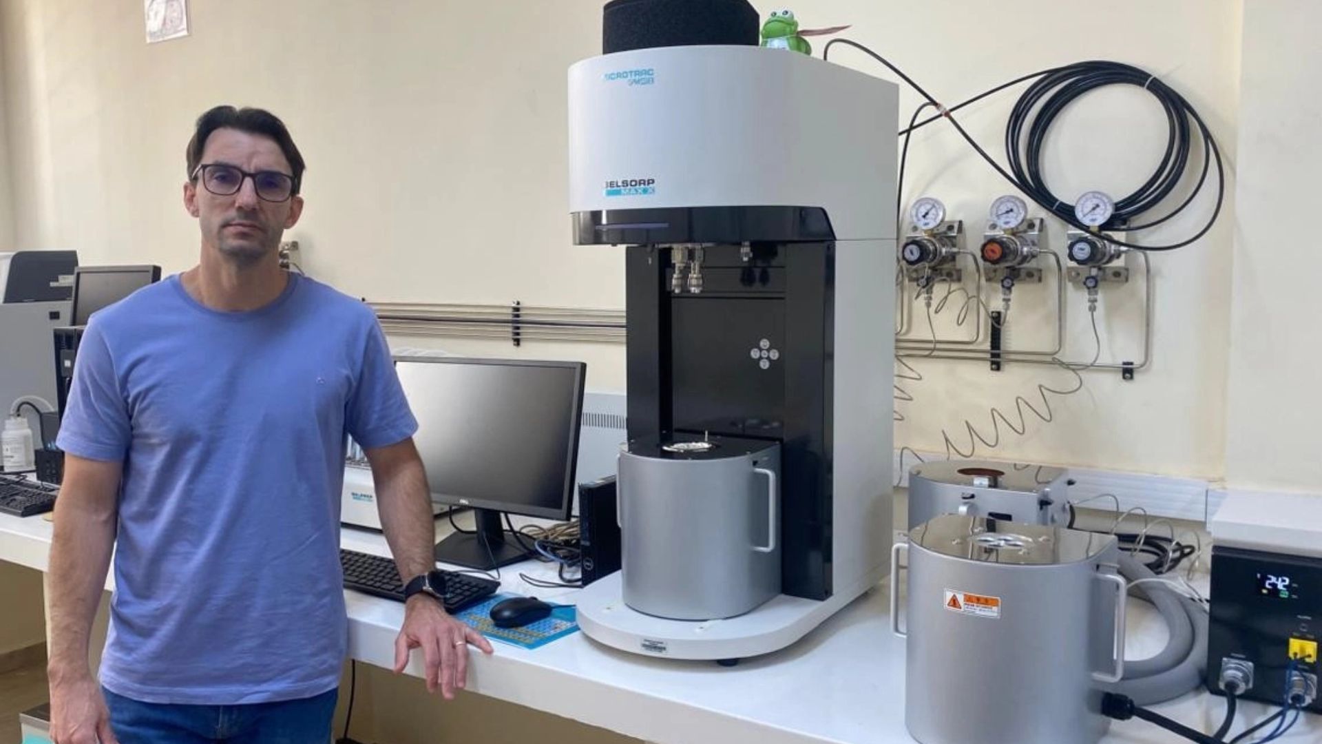 Pesquisador ao lado de equipamento de laboratório utilizado em análises de materiais e pesquisas tecnológicas.