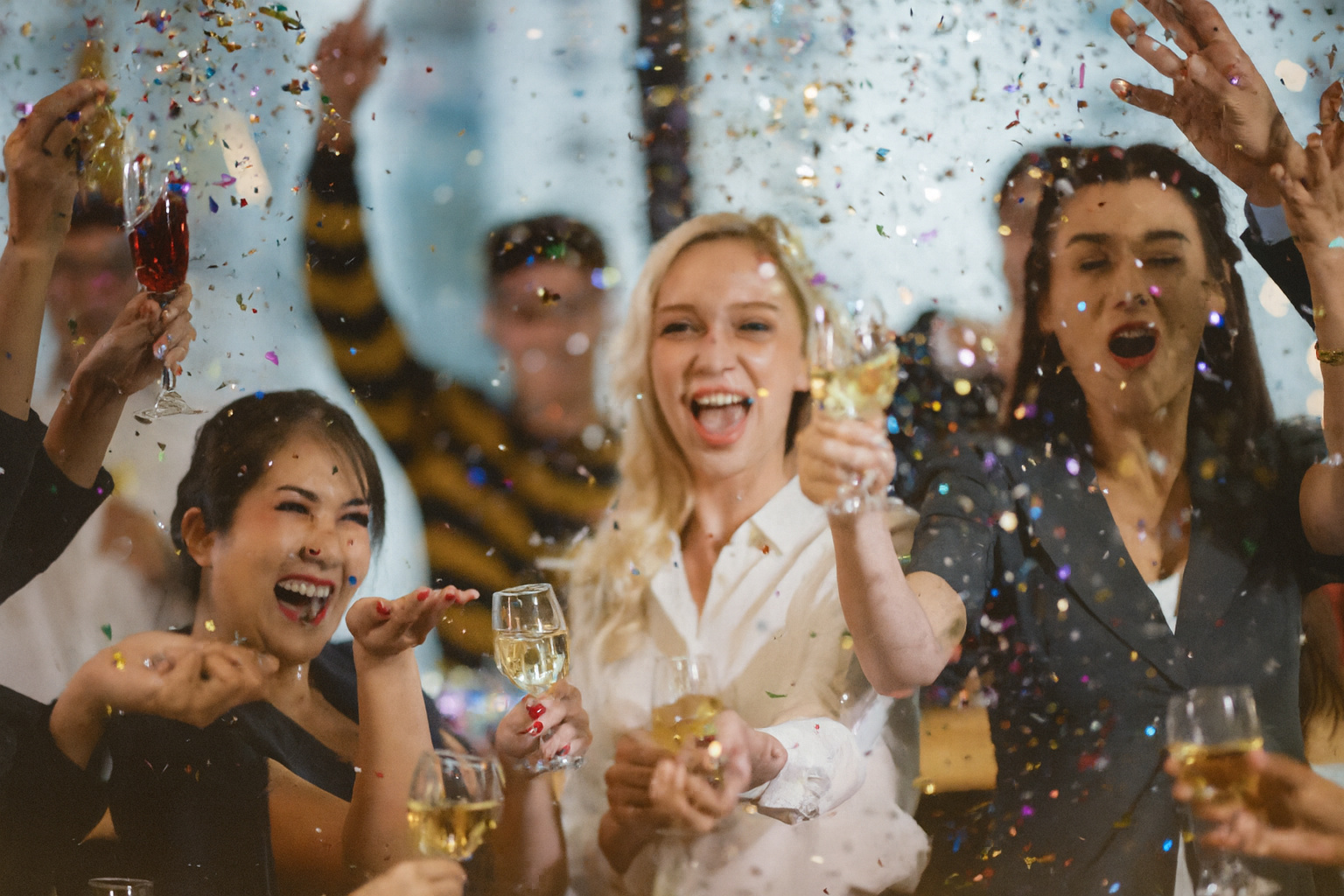 Funcionários comemorando em festa corporativa com bebidas e confetes, simbolizando ambiente social que exige atenção ao comportamento profissional.
