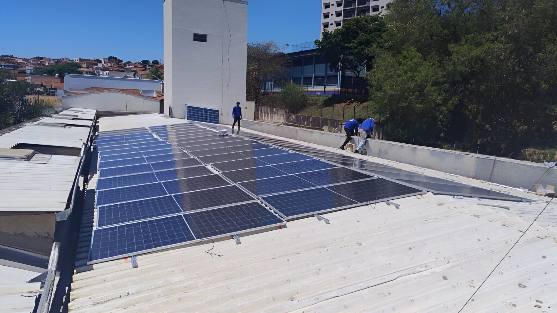 Instalação de painéis solares no telhado de um prédio em Piracicaba, com técnicos trabalhando na montagem da micro-usina fotovoltaica
