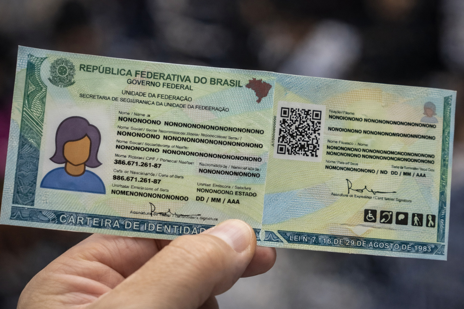 Nova Carteira de Identidade Nacional do Brasil sendo segurada por uma mão, com CPF único, QR Code e elementos de segurança visíveis.