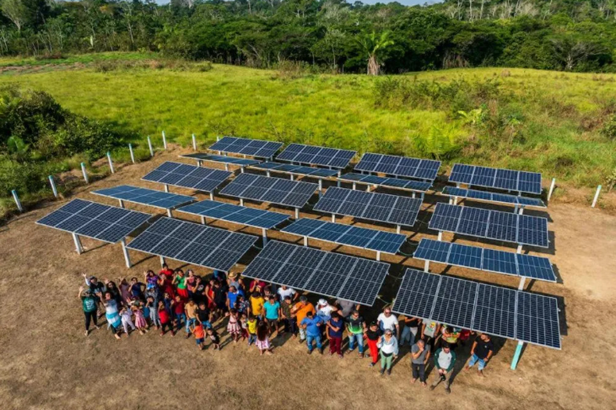 Sistema solar comunitário em Vila Limeira com moradores reunidos ao lado das placas fotovoltaicas.