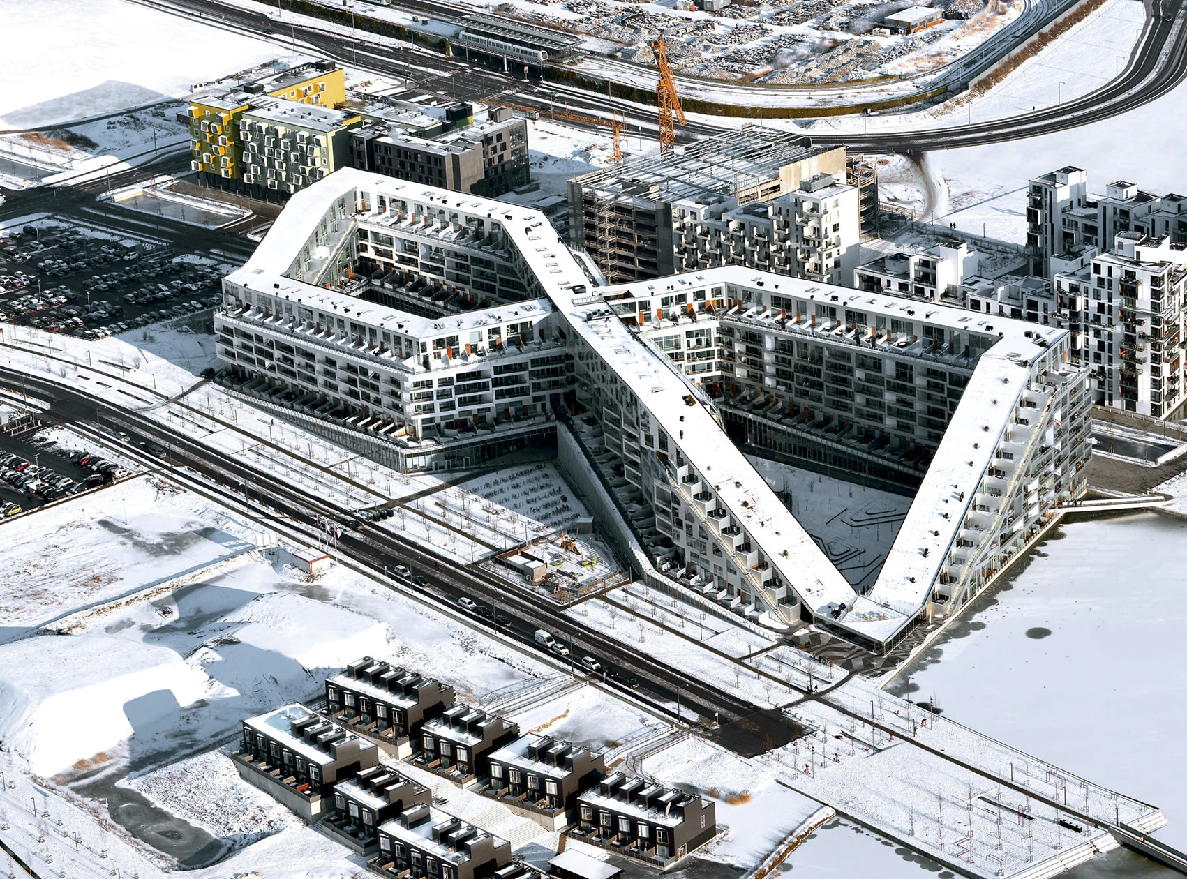 Para comprimir um bairro inteiro em 62 mil m² em Copenhague, engenheiros empilharam 475 moradias sobre 10 mil m² de comércio e criaram uma rampa contínua que sobe até o 10º andar dentro do complexo 8 House