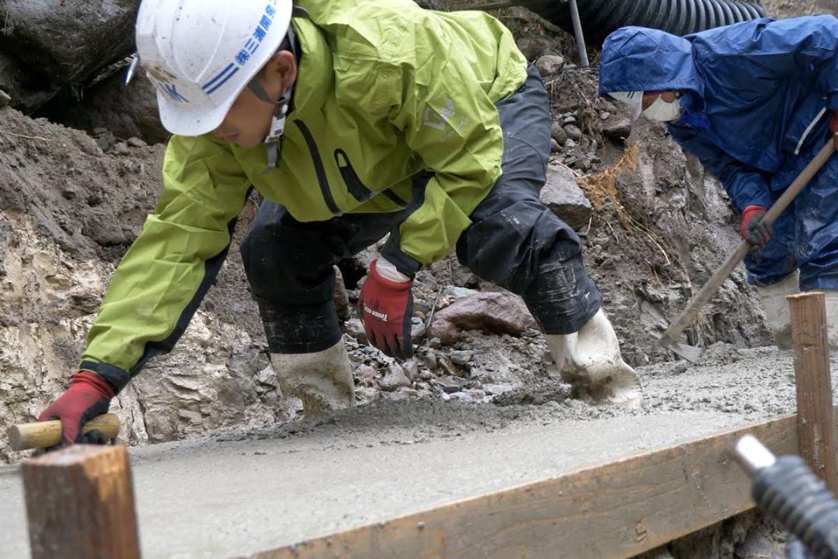 engenheiros japoneses unem concreto e cofragem no leito do rio para reduzir erosão e conter enchentes, com obras discretas que guiam afluentes e reforçam a margem principal.