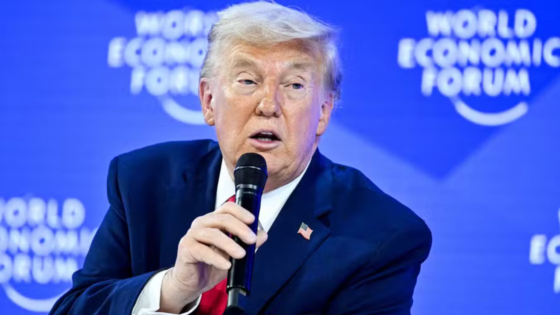 Donald Trump discursa durante o Fórum Econômico Mundial, em Davos, segurando um microfone diante do painel do World Economic Forum.