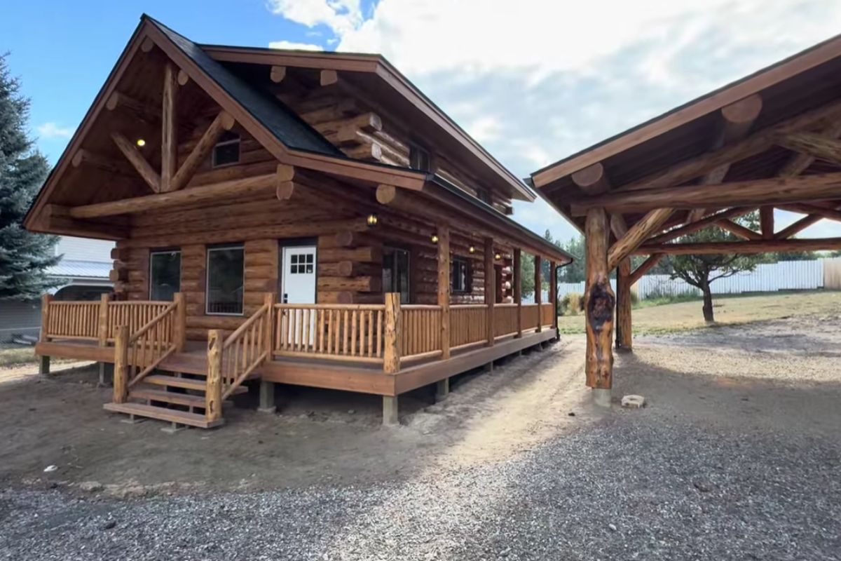 Cabana de madeira Denali 24x32 usa toras maiores, teto abobadado e isolamento no telhado, com garagem coberta integrada, para entregar eficiência térmica, layout com loft e soluções de manutenção em um conjunto rústico e técnico.