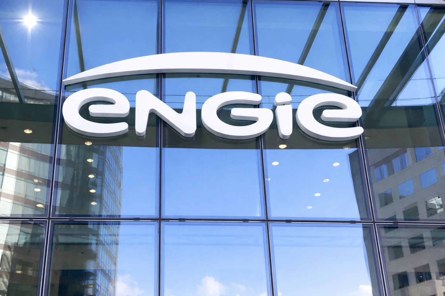 Fachada envidraçada da sede da empresa ENGIE com logotipo em destaque, sob céu azul em dia ensolarado.