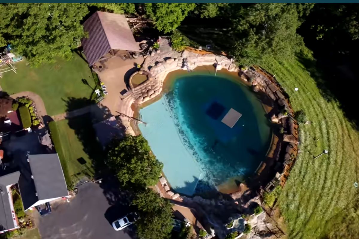 Conheça a piscina absurda de 500 mil galões de 1,9 milhão de litros, com cachoeira, balanço de corda e sistema de filtragem criado no quintal após 29 anos de obra e manutenção.