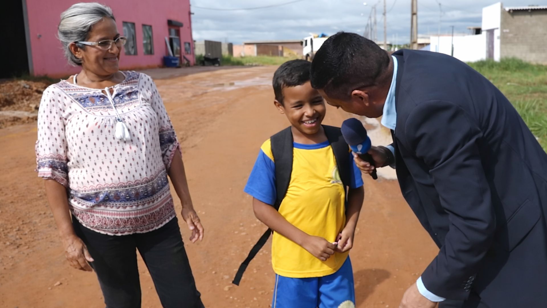 Menino de 9 anos caminhando com a mãe por estrada de terra a caminho da escola após percorrer 6 km diariamente.