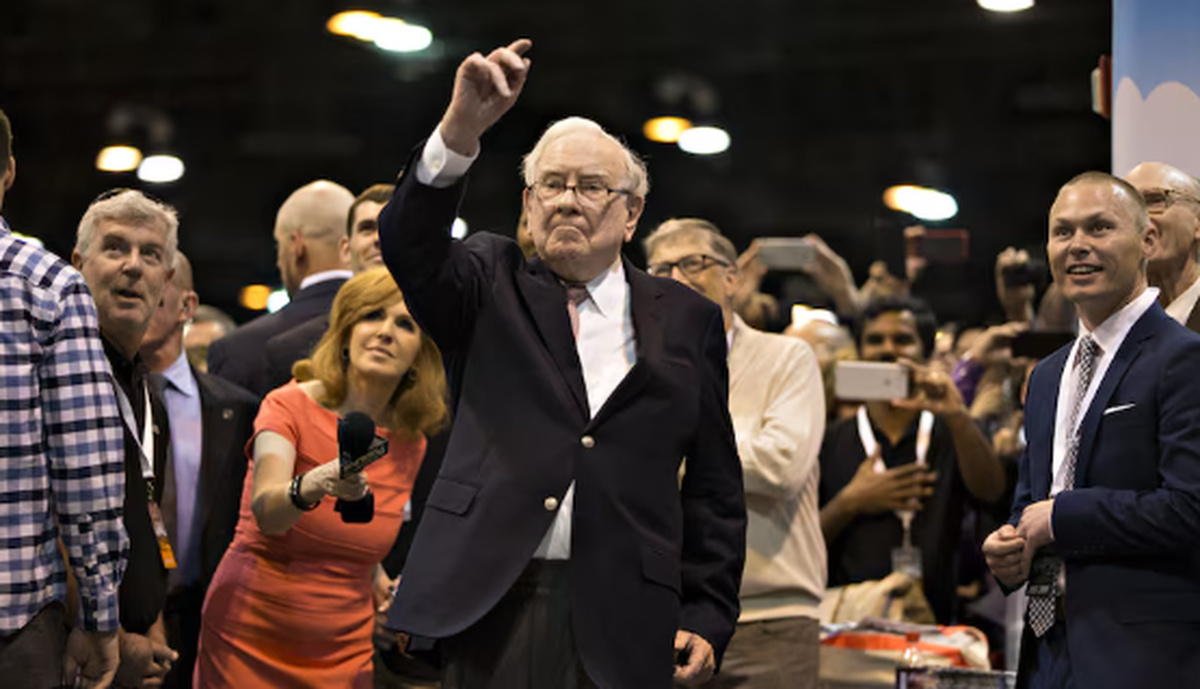 Warren Buffett em evento público com investidores, cercado por apoiadores e executivos, em contexto relacionado a decisões estratégicas da Berkshire Hathaway no mercado financeiro.