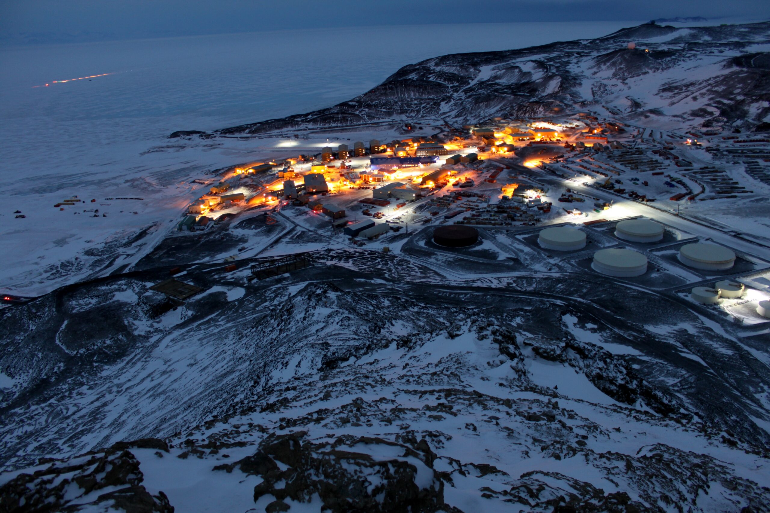 Estação McMurdo na Antártica funciona como cidade de 1.200 pessoas a -50°C com usina dessalinizadora produzindo 170 mil litros de água por dia, bombeiros, central telefônica, rádio FM e até 2 caixas eletrônicos operando 24 horas no lugar mais isolado da Terra onde aviões só pousam 4 meses por ano